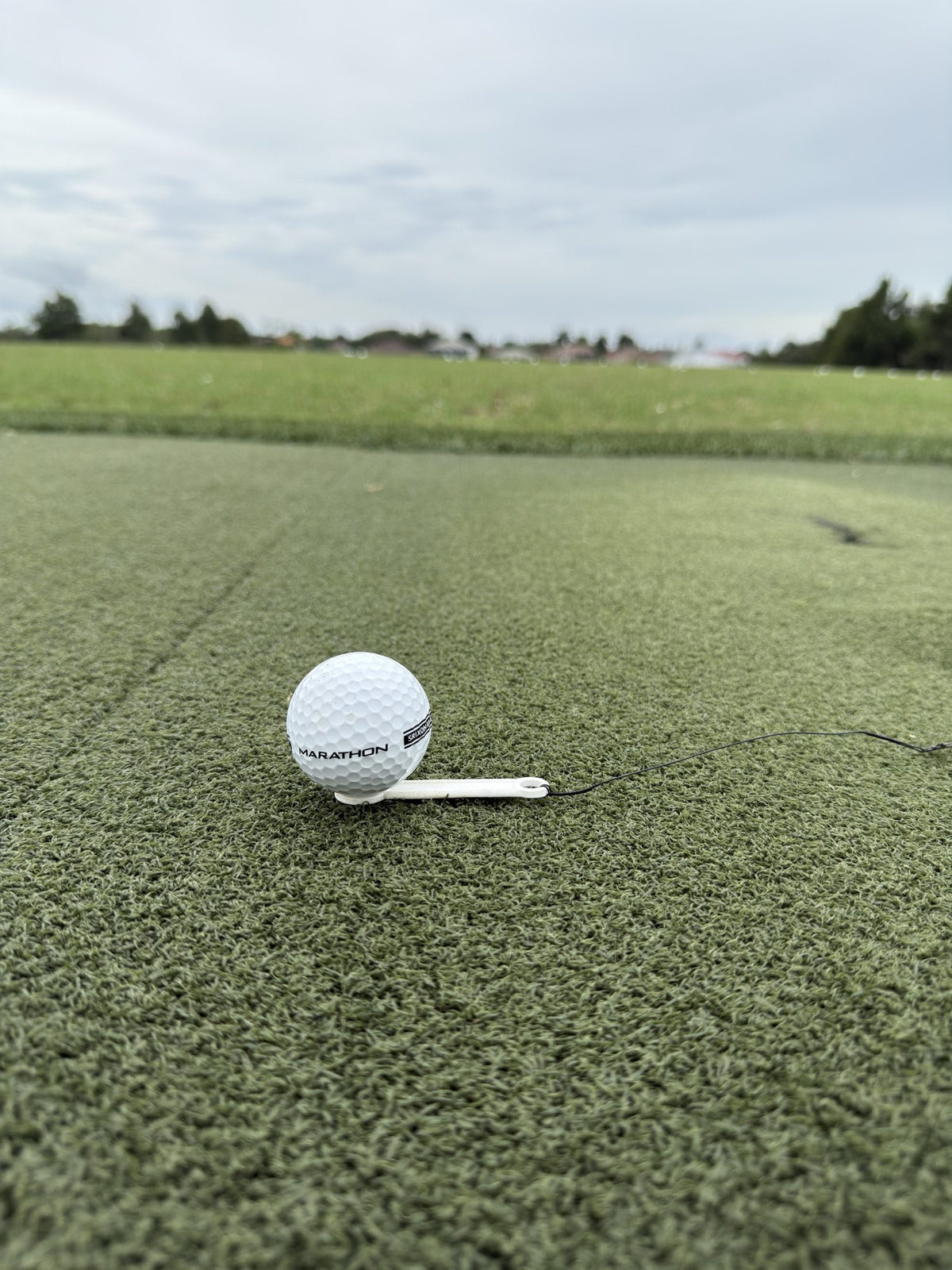 Golf ball teed up on a hitting mat with The Perfect Divot