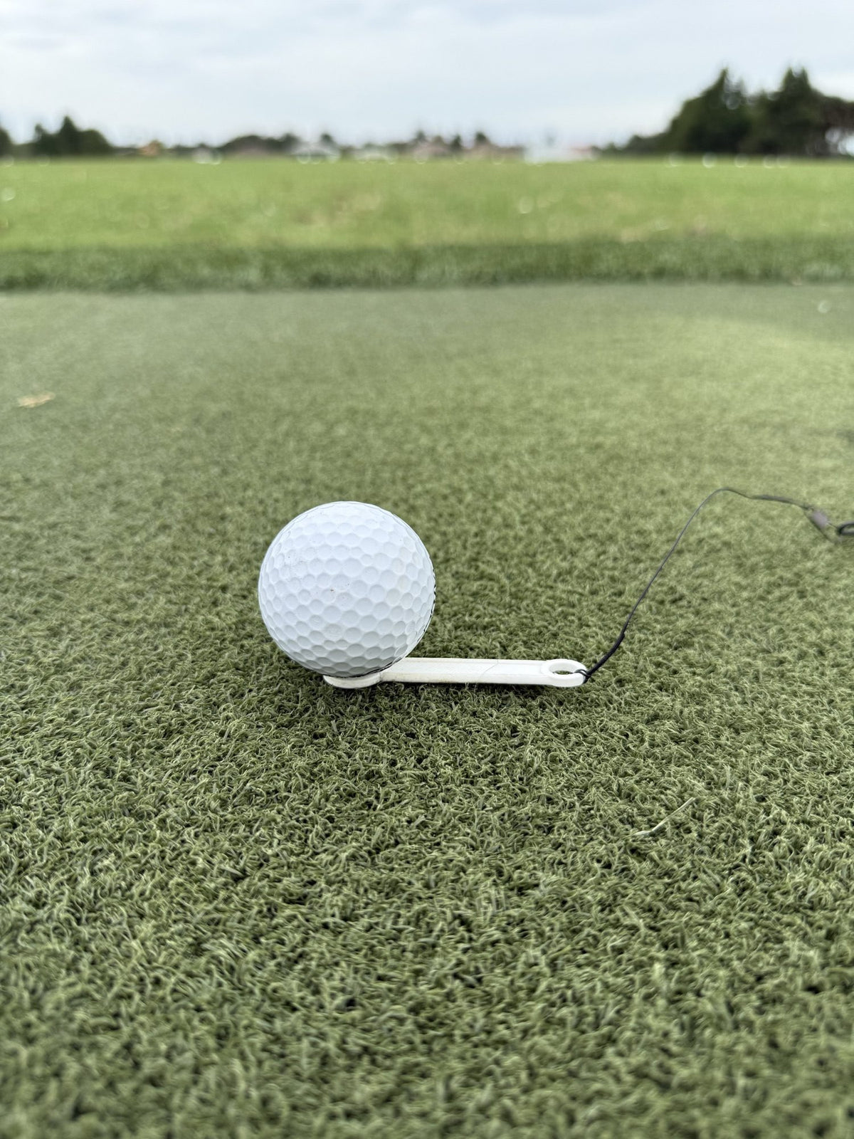 Close-up of a golf ball on The Perfect Divot tee on a hitting mat
