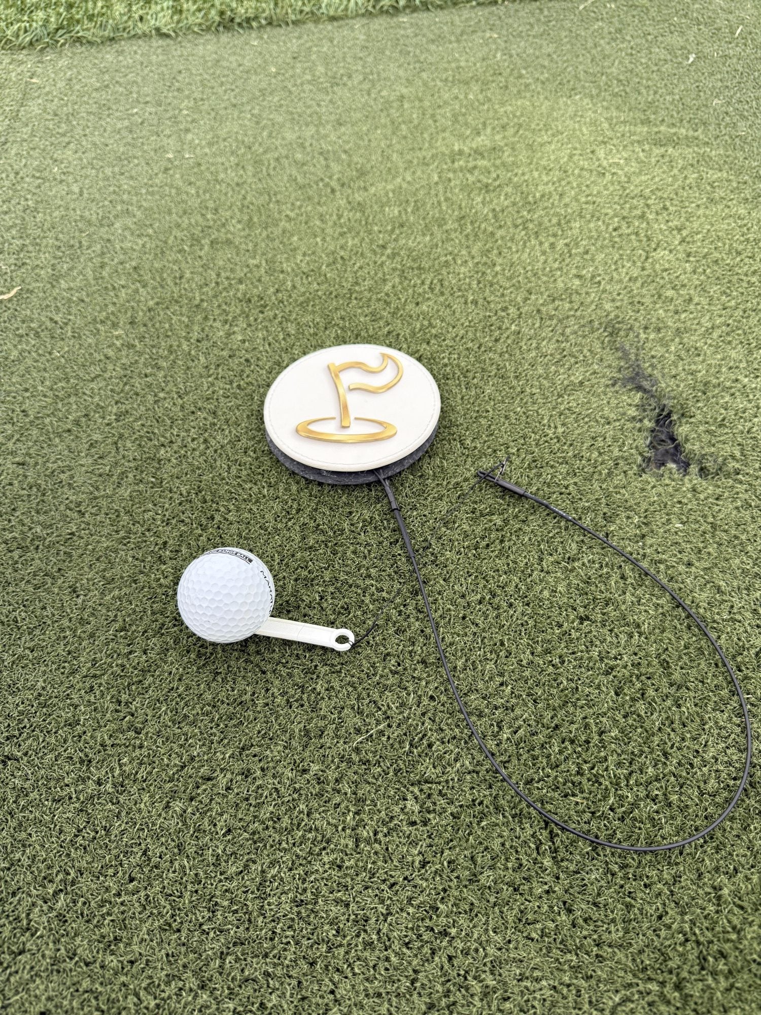 The Perfect Divot disc and golf ball on a hitting mat