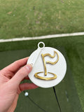 Close-up of The Perfect Divot white disc with gold flag logo