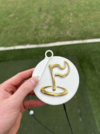 Close-up of The Perfect Divot white disc with gold flag logo