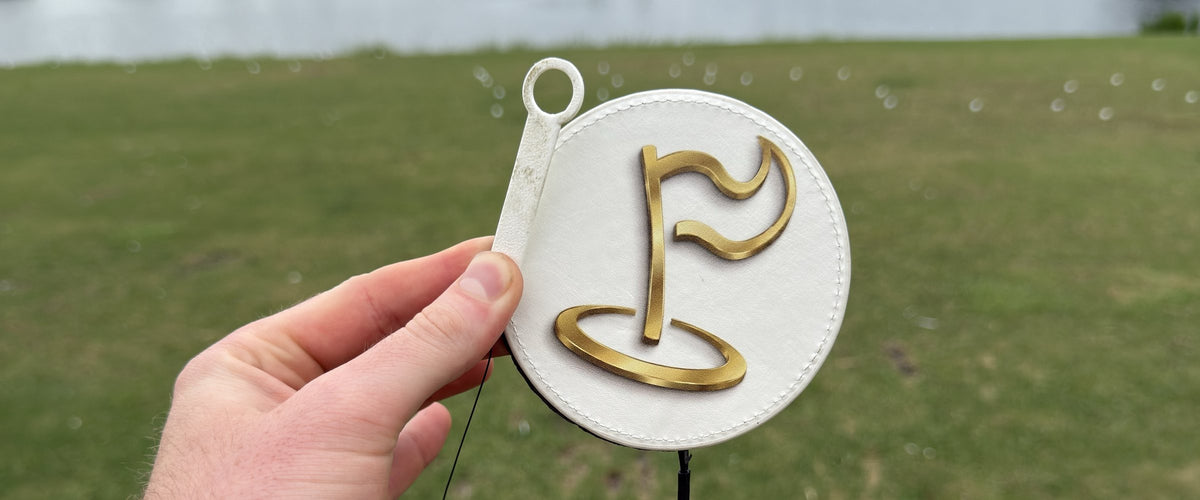 The Perfect Divot disc held up at a driving range by a lake